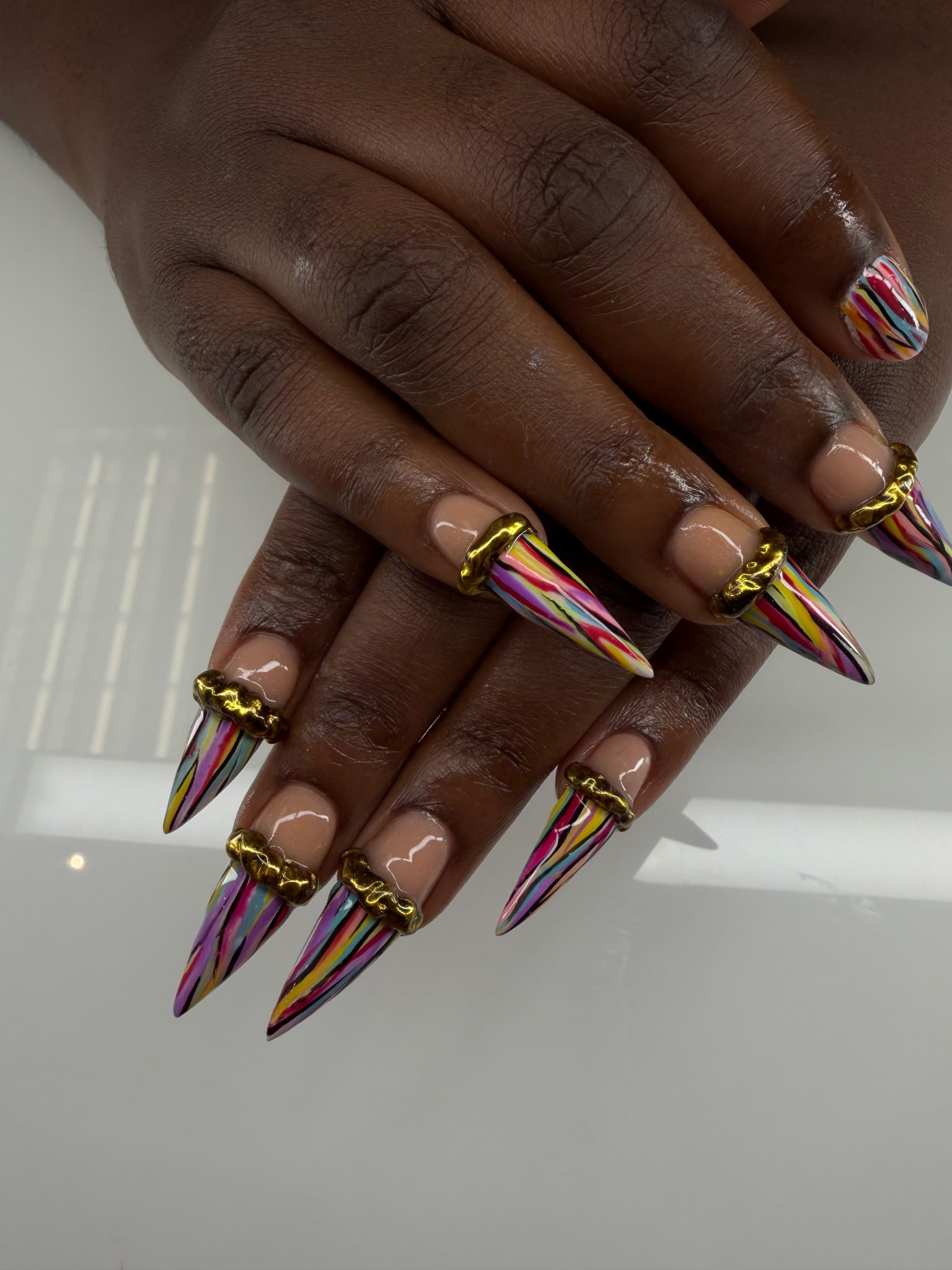 Stiletto nails with gold accents and multicolor line art