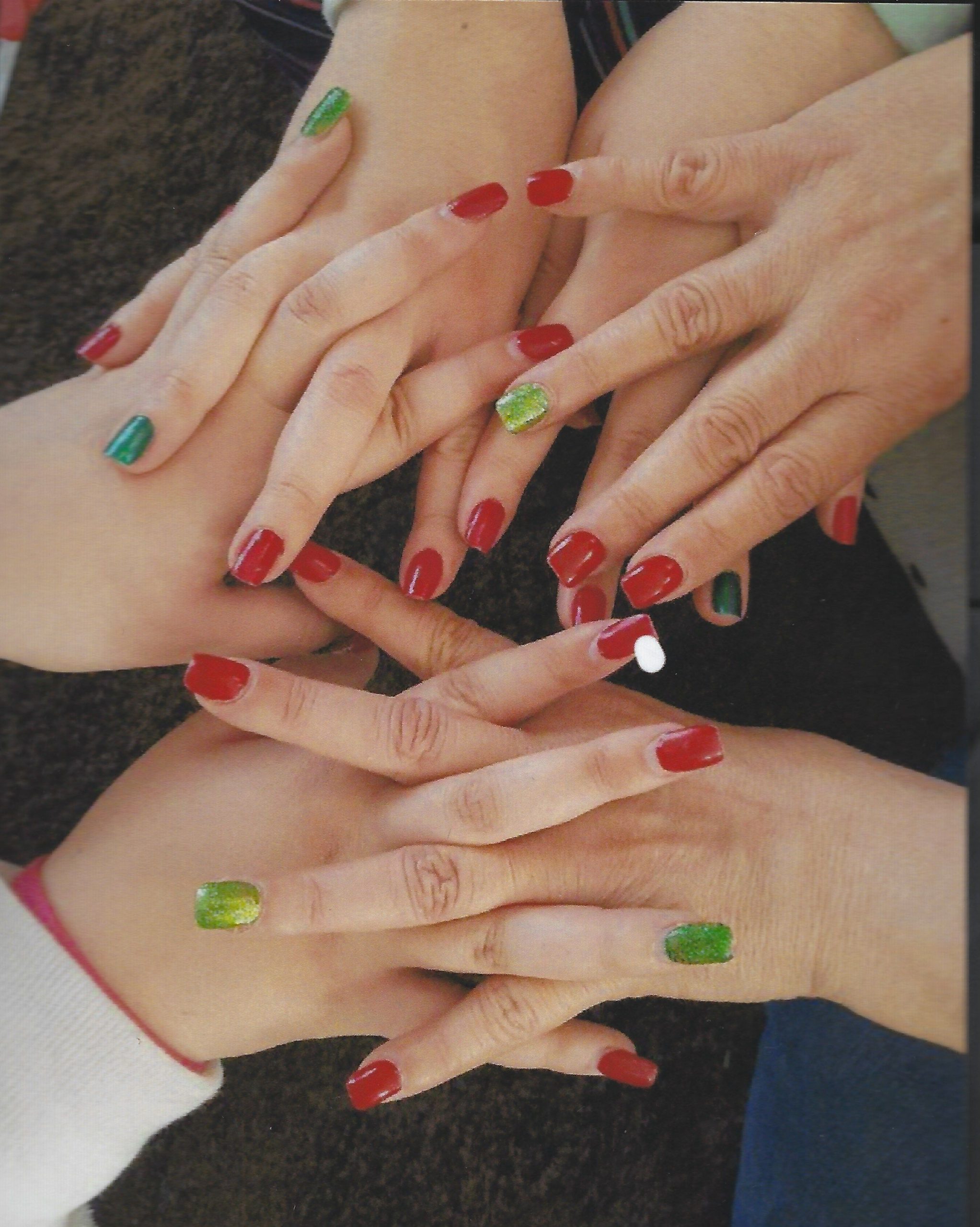 Group of hands showing red and green manicures
